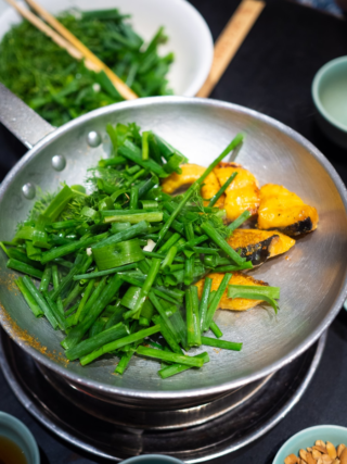 Fish and green vegetables being cooked in a pan.